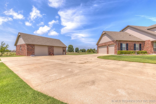 view of side of home with concrete driveway, brick siding, a lawn, and roof with shingles