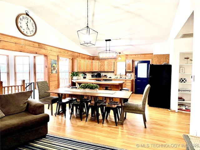 dining space with lofted ceiling, visible vents, a chandelier, and light wood-style flooring