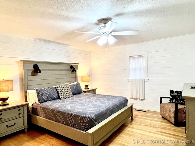 bedroom featuring visible vents, a textured ceiling, light wood-style flooring, and a ceiling fan
