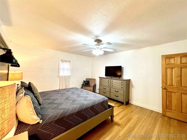 bedroom featuring baseboards, ceiling fan, light wood-style flooring, and a textured ceiling