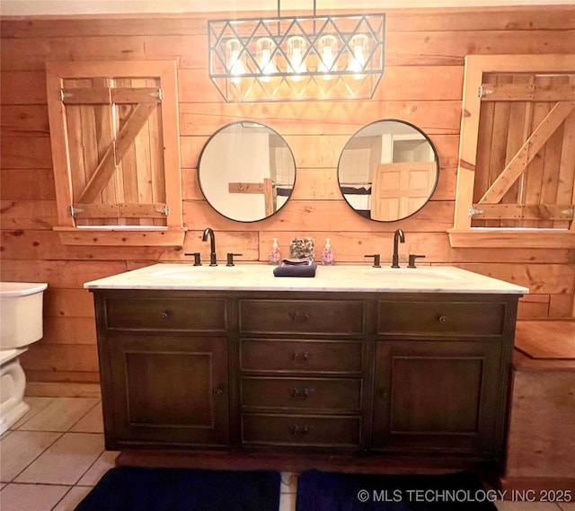 bathroom with toilet, double vanity, wooden walls, and a sink