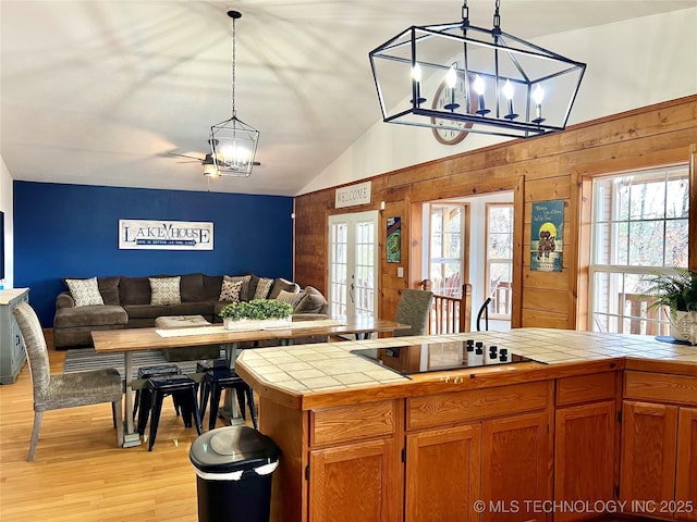 kitchen with tile counters, open floor plan, an inviting chandelier, black electric stovetop, and french doors