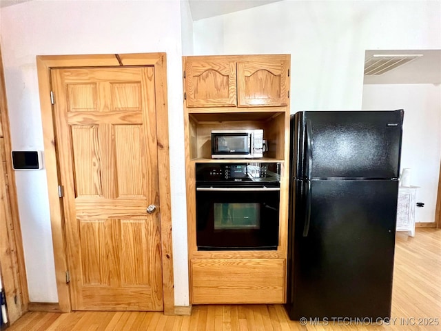 kitchen with light wood-type flooring, black appliances, baseboards, and visible vents