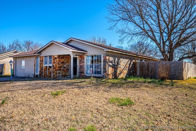 single story home with brick siding, fence, and a front yard