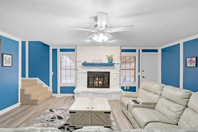 living room featuring a fireplace, wood finished floors, a ceiling fan, baseboards, and stairs