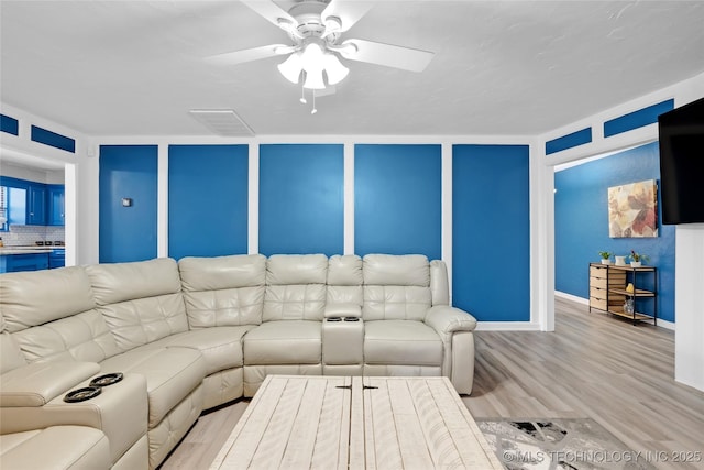 living room featuring a ceiling fan, a decorative wall, and wood finished floors