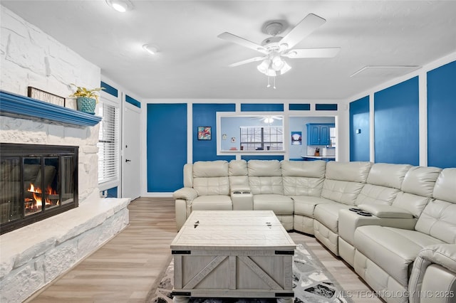 living area with light wood finished floors, ceiling fan, and a fireplace