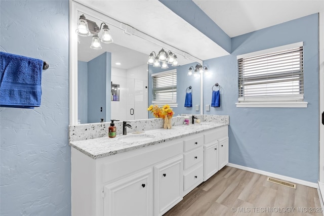 full bathroom featuring a stall shower, a sink, baseboards, and wood finished floors