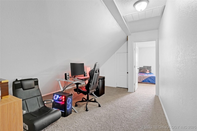 office area featuring lofted ceiling, visible vents, a textured wall, carpet flooring, and baseboards