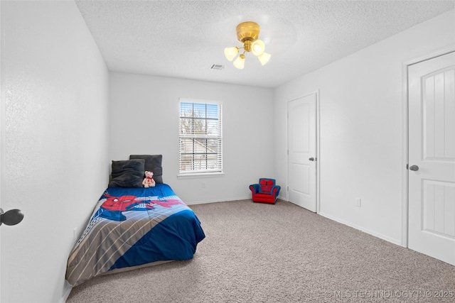 carpeted bedroom featuring a textured ceiling, visible vents, and baseboards