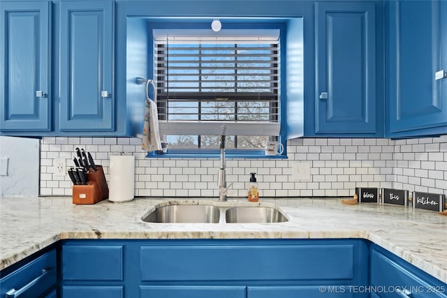 kitchen featuring blue cabinetry, backsplash, and a sink