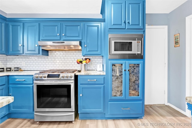 kitchen with blue cabinets, stainless steel gas range, under cabinet range hood, and built in microwave