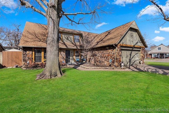 view of front facade with stone siding, a front lawn, a shingled roof, and fence