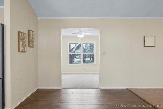 spare room with ornamental molding, wood finished floors, a ceiling fan, and baseboards