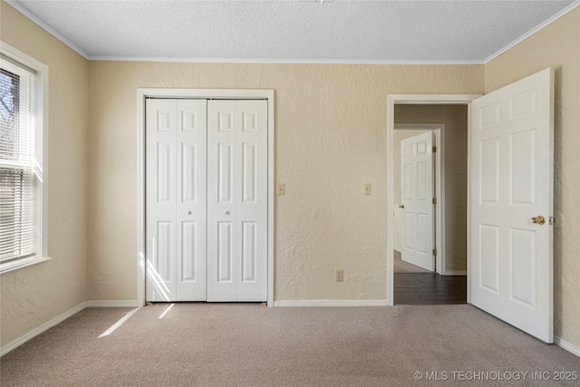 unfurnished bedroom featuring carpet floors, multiple windows, and a textured wall