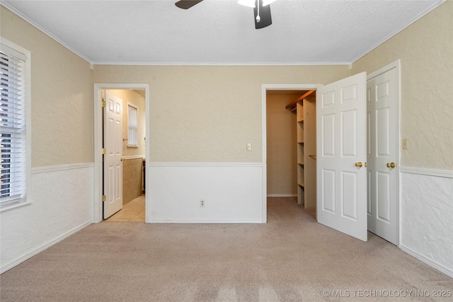 unfurnished bedroom featuring crown molding, carpet flooring, a textured wall, and a textured ceiling