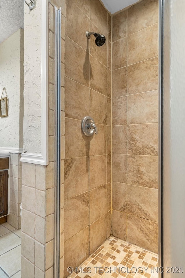 full bath with a shower stall and wainscoting