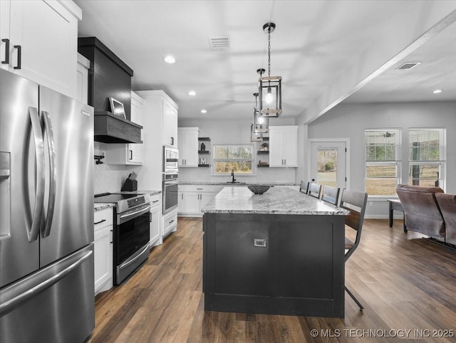 kitchen with open shelves, stainless steel appliances, visible vents, a kitchen island, and a sink