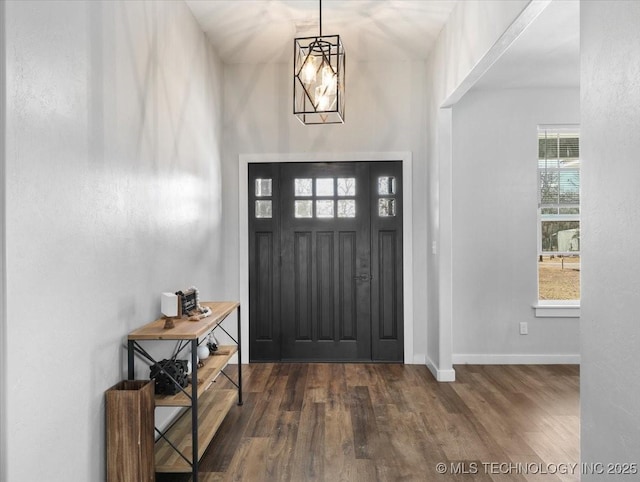 foyer entrance with a notable chandelier, baseboards, and dark wood-type flooring