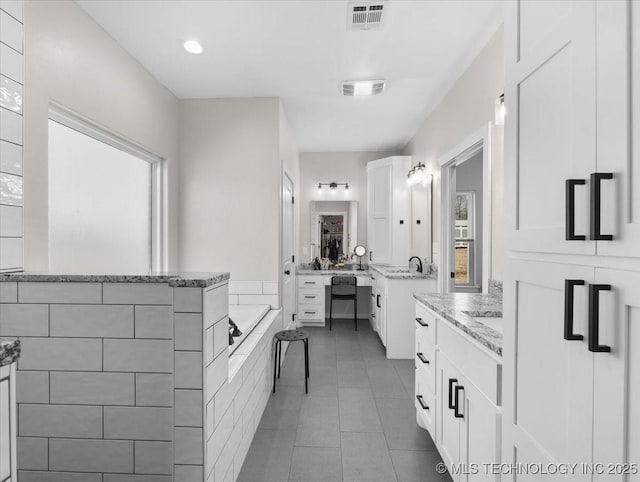 bathroom featuring two vanities, tile patterned flooring, visible vents, and a garden tub