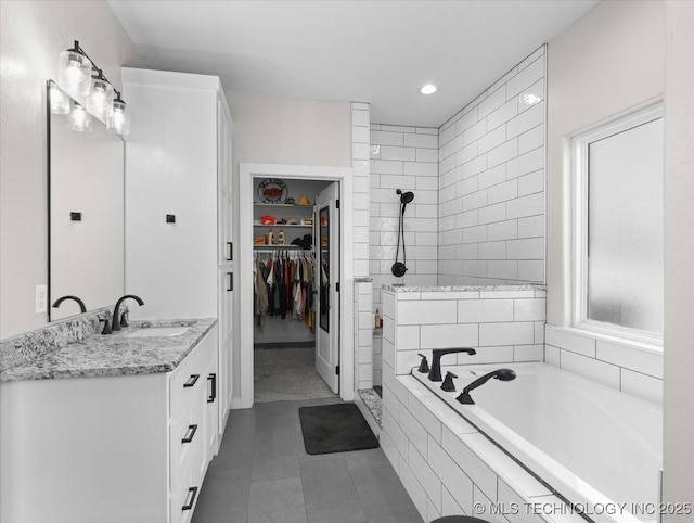 bathroom featuring vanity, a spacious closet, tiled shower, a bath, and tile patterned floors