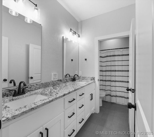 bathroom with double vanity, a sink, toilet, and tile patterned floors