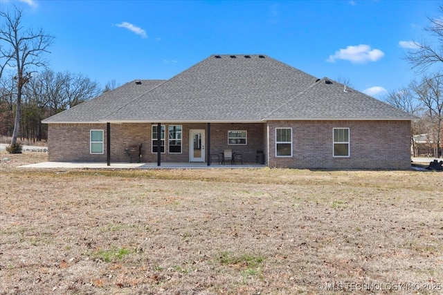 rear view of property featuring brick siding, a patio area, and a shingled roof