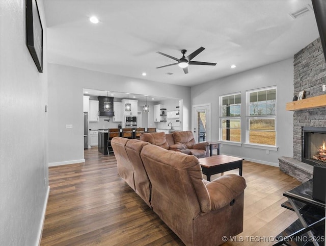 living area featuring recessed lighting, a fireplace, wood finished floors, and baseboards