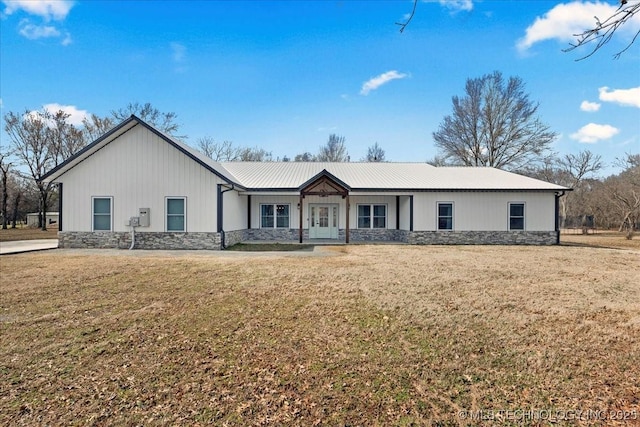 ranch-style house featuring stone siding, metal roof, and a front yard