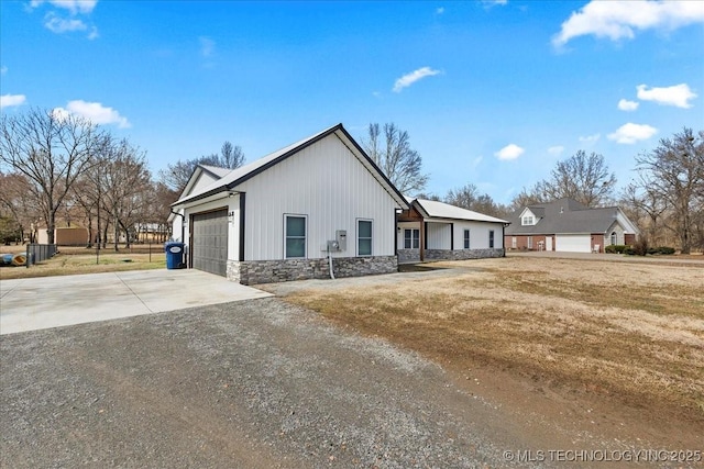 view of front facade with a garage, stone siding, concrete driveway, and a front yard