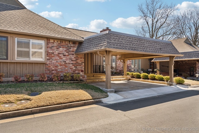 exterior space featuring brick siding, mansard roof, and roof with shingles