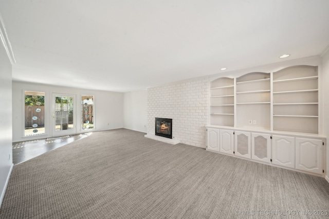 unfurnished living room featuring recessed lighting, light carpet, built in features, and a fireplace