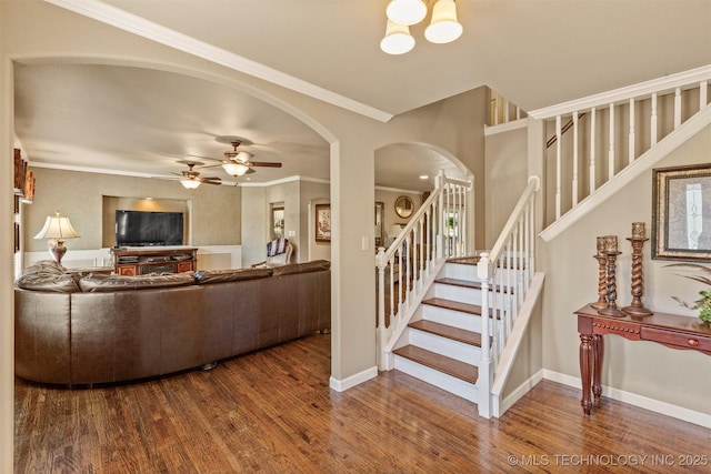 living area with baseboards, arched walkways, stairway, wood finished floors, and crown molding