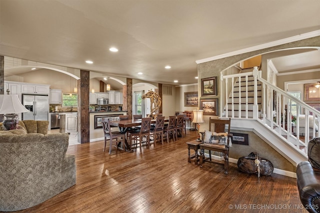 living area with arched walkways, baseboards, stairs, dark wood-style floors, and crown molding