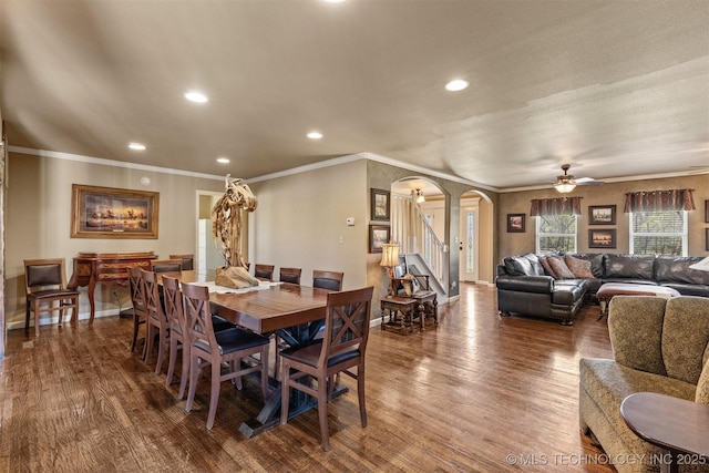 dining space featuring arched walkways, dark wood finished floors, and baseboards