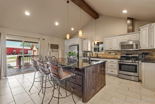 kitchen with beam ceiling, backsplash, appliances with stainless steel finishes, a sink, and a kitchen breakfast bar