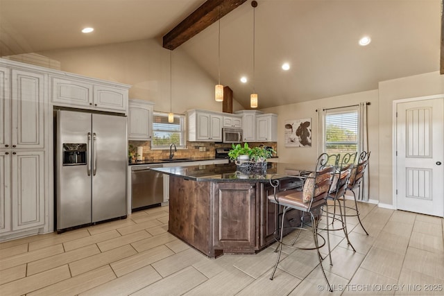 kitchen with a breakfast bar, stainless steel appliances, tasteful backsplash, a kitchen island, and a sink