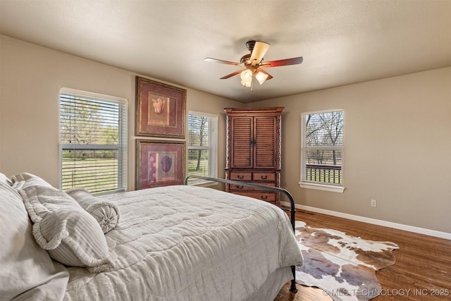 bedroom with a ceiling fan, a textured ceiling, baseboards, and wood finished floors