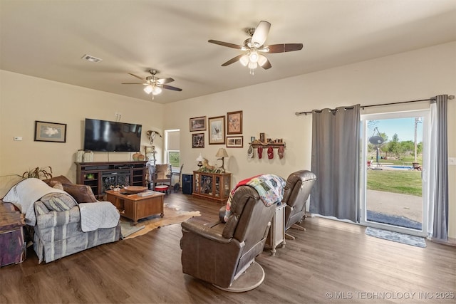 living room featuring a ceiling fan, visible vents, and wood finished floors