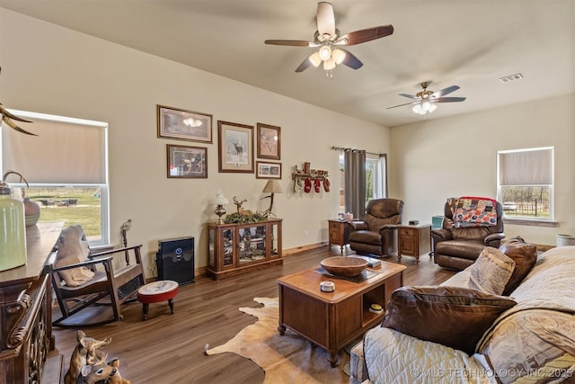 living room with a ceiling fan, baseboards, visible vents, and wood finished floors