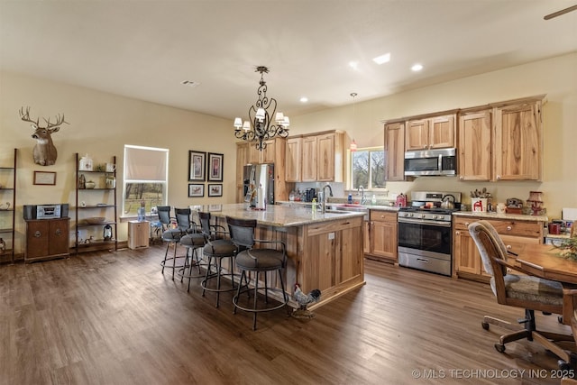 kitchen featuring light stone counters, a breakfast bar area, stainless steel appliances, dark wood-type flooring, and a kitchen island with sink