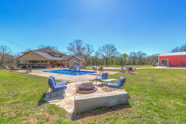 outdoor pool featuring a yard, a fire pit, an outdoor structure, and a patio