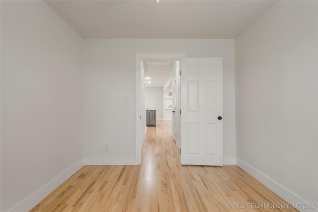 empty room featuring light wood-type flooring and baseboards