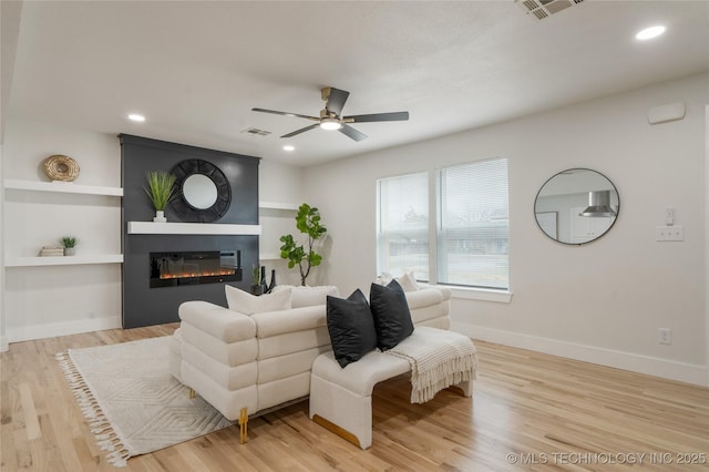 living room with baseboards, a fireplace, visible vents, and light wood-style floors