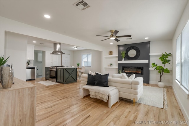 living area featuring recessed lighting, a large fireplace, a ceiling fan, visible vents, and light wood-type flooring