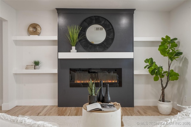 room details with built in features, a fireplace, visible vents, wood finished floors, and baseboards