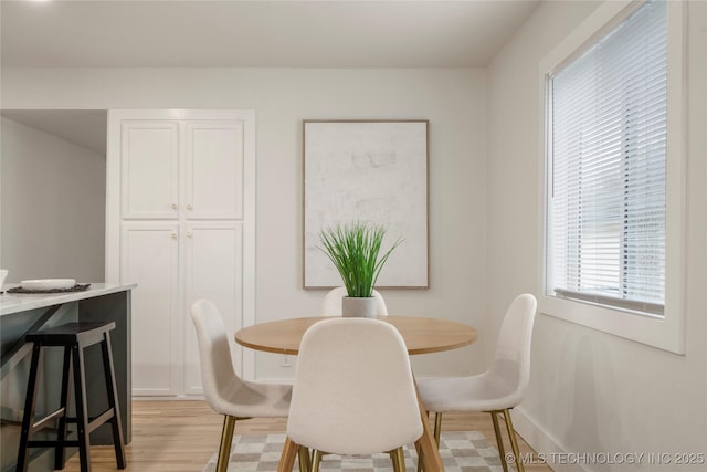 dining space with light wood finished floors and baseboards