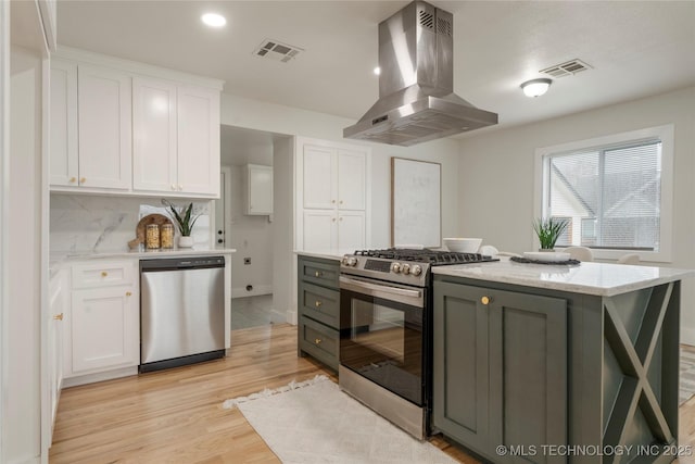 kitchen with visible vents, light wood-style flooring, appliances with stainless steel finishes, island exhaust hood, and white cabinetry