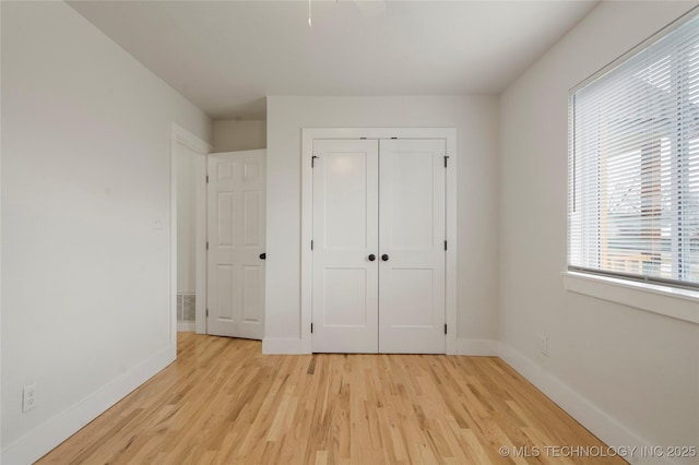 unfurnished bedroom with light wood-style floors, a closet, and baseboards