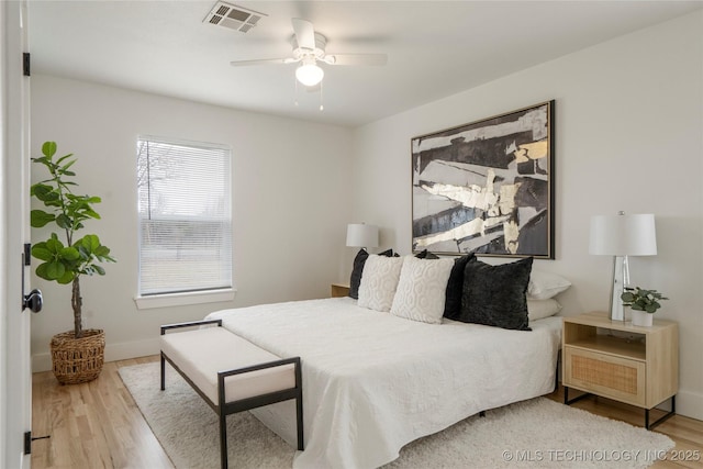 bedroom featuring visible vents, ceiling fan, baseboards, and wood finished floors